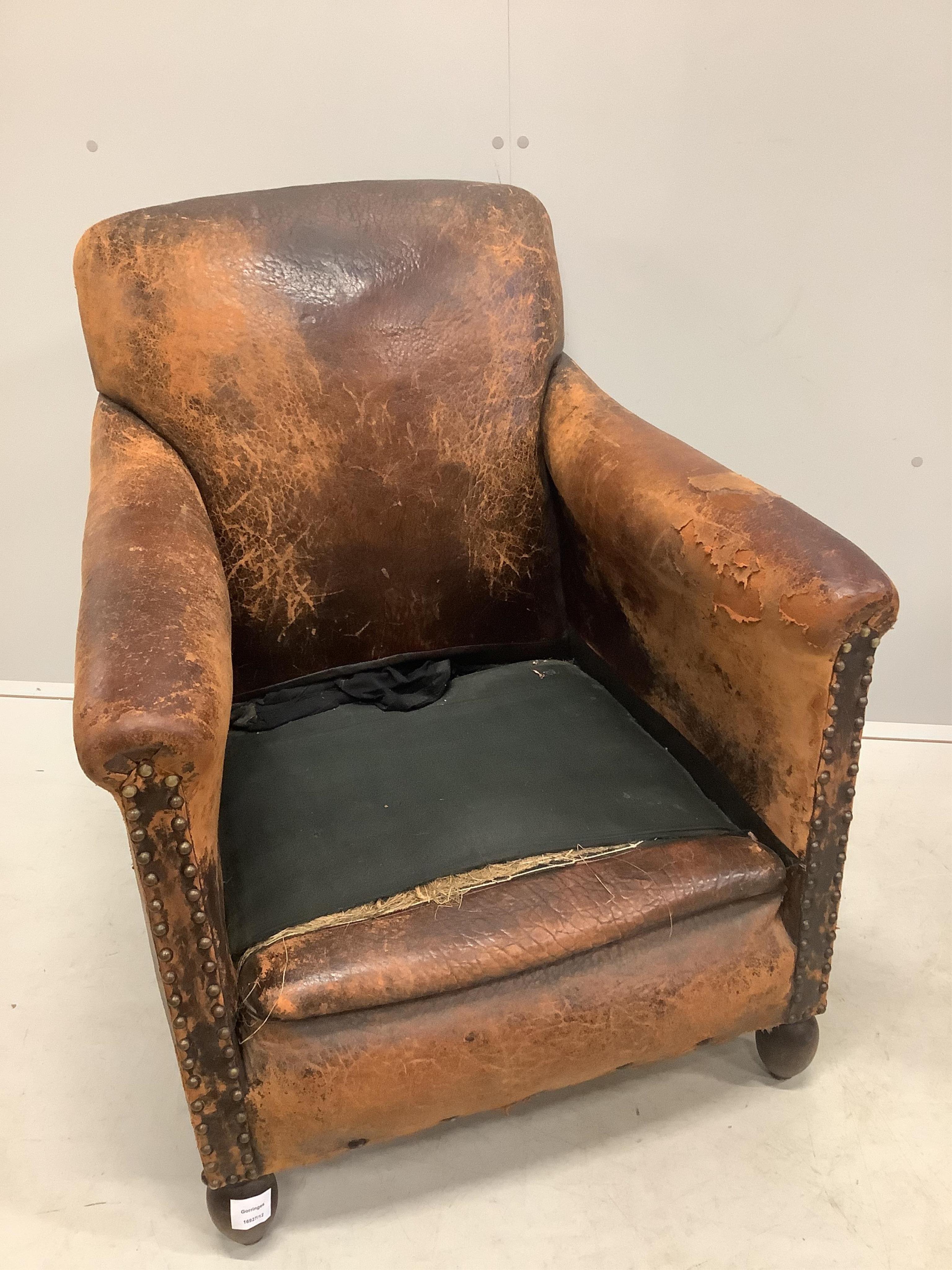 A pair of early 20th century French leather club armchairs, width 73cm, depth 74cm, height 83cm. Condition - poor to fair